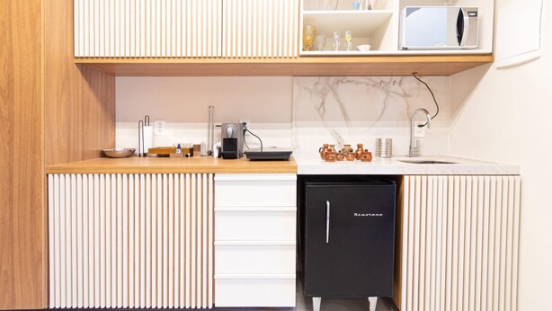 A modern kitchen with a wooden countertop, a built-in microwave, a sink, and a black refrigerator. - Conforto no île de Pipa por Carpediem (Tibau do Sul)