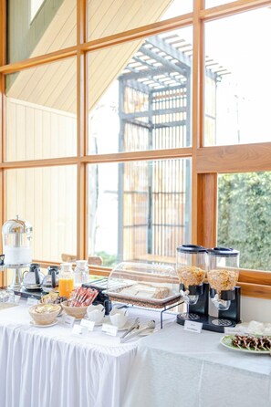 Montaje de un bufé de desayuno con diversas opciones de comida y una estación de café.