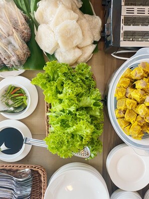 Una mesa con diversos alimentos, incluyendo carne a la parrilla, pasteles de arroz, lechuga y albóndigas amarillas.