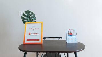 A framed sign on a table with a RedDoorz logo and a website URL, a potted plant, and a RedDoorz brochure.