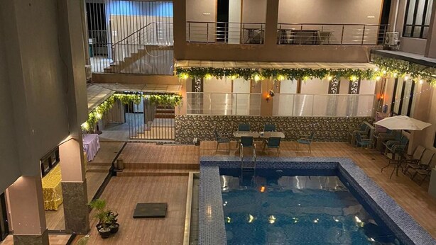 Un área de piscina interior con varios niveles, una piscina con azulejos, asientos alrededor y una escalera que lleva a un nivel superior.
