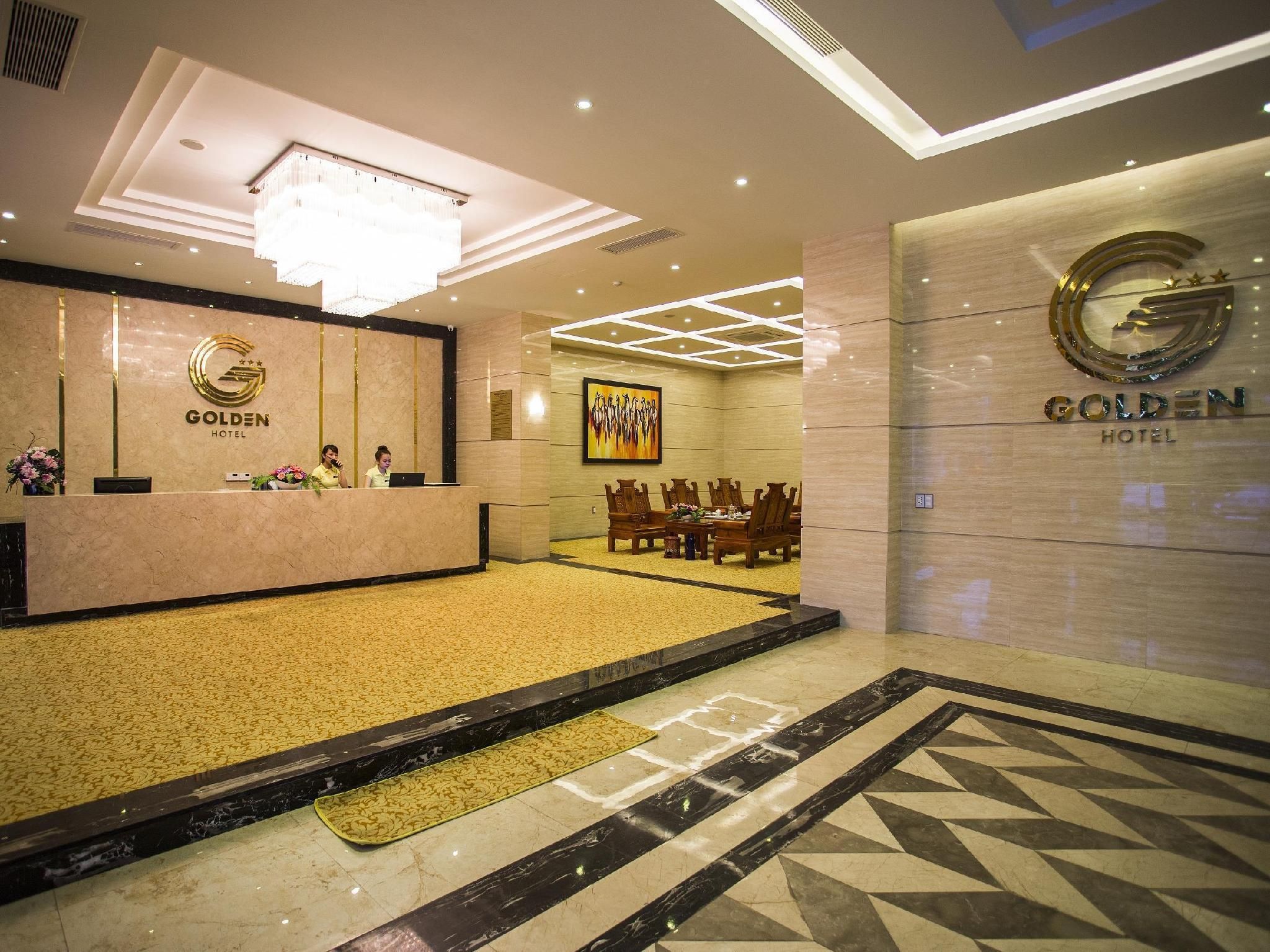 A hotel reception area with a marble counter, a chandelier, and a conference room with wooden furniture.