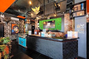 A modern reception area with a counter, a green wall, and a motivational quote. - Sans Hotel Roxy Jakarta (Jakarta)