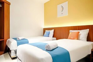 A hotel room with two beds, wooden headboards, and a wall-mounted logo. - Sans Hotel Roxy Jakarta (Jakarta)