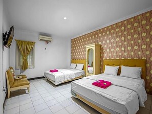 A hotel room with two beds, a chair, a mirror, and a patterned wall. - Hotel Cempaka Sari (Jakarta)