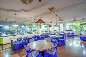 A spacious restaurant with multiple round tables and chairs, large windows, and ceiling fans. - Hotel Cempaka Sari (Jakarta)