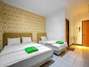 A hotel room with two beds, a patterned wallpaper, a wooden door, and a tiled floor. - Hotel Cempaka Sari (Jakarta)
