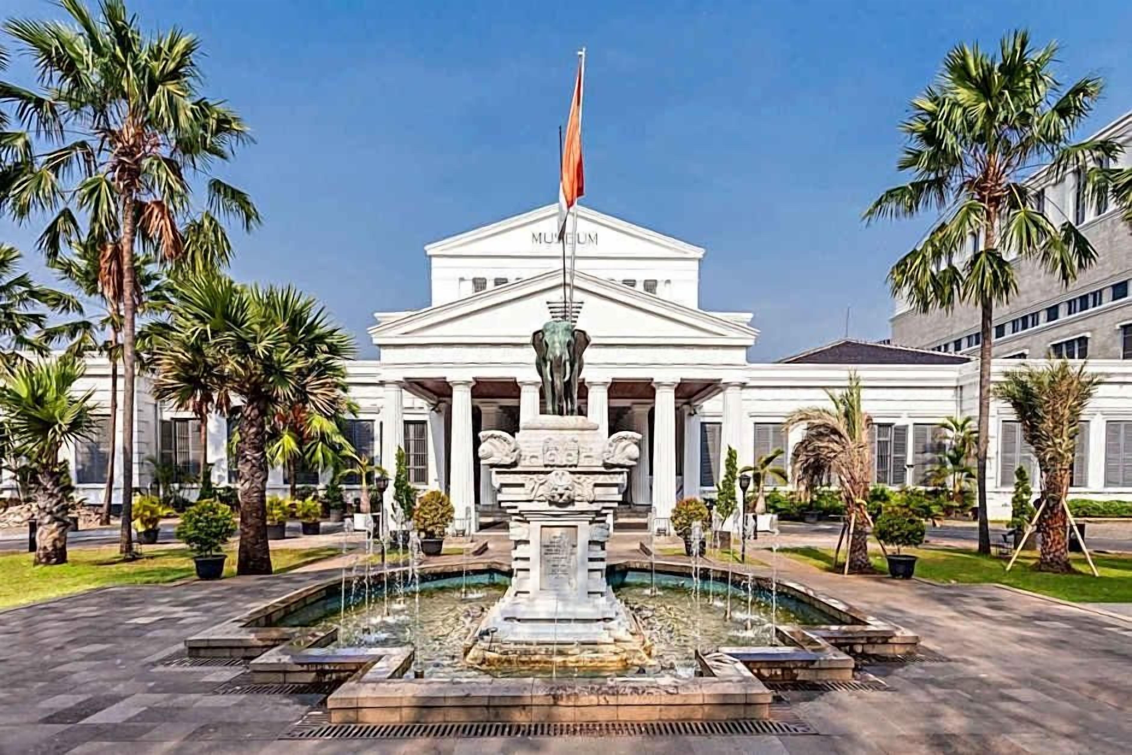 A building with a central fountain, palm trees, and a flag.