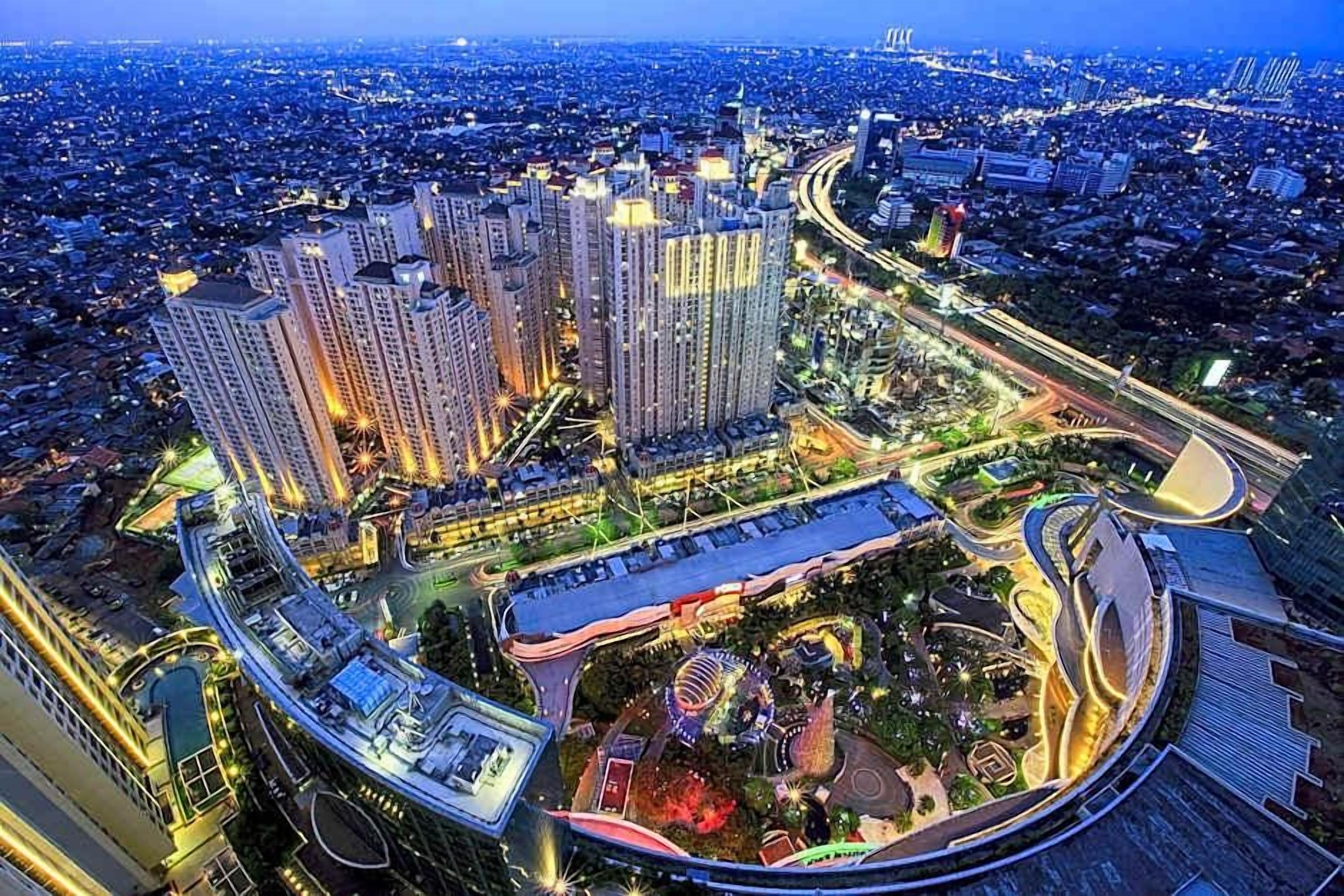 A high-rise building complex with multiple floors, surrounded by a well-lit urban area with roads and greenery.