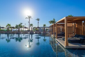 A pool with clear water, surrounded by lounge chairs and palm trees. - Ammades All Suites Beach Hotel - Adults Only (Rhodes)