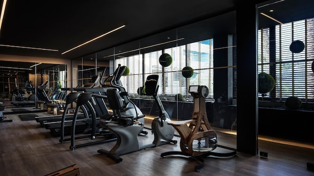 A modern gym with exercise equipment, large windows, and a wooden floor. - Ammades All Suites Beach Hotel - Adults Only (Rhodes)