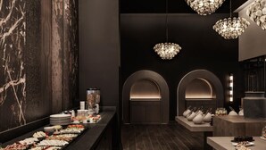 A modern interior with a marble wall, a buffet with various food items, and elegant chandeliers. - Ammades All Suites Beach Hotel - Adults Only (Rhodes)