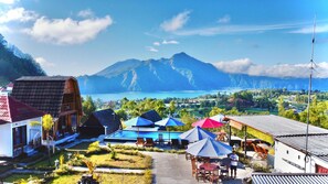 A coastal resort with a pool area, outdoor seating, and a view of the ocean and mountains. - Bunbulan Cottage Lake View (Kintamani)