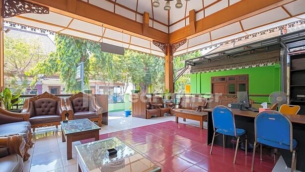 A spacious lobby with traditional wooden furniture, a green wall, and a view of the outdoors. - Hotel Wisata Ziarah Sunan Bonang Syariah (Tuban)