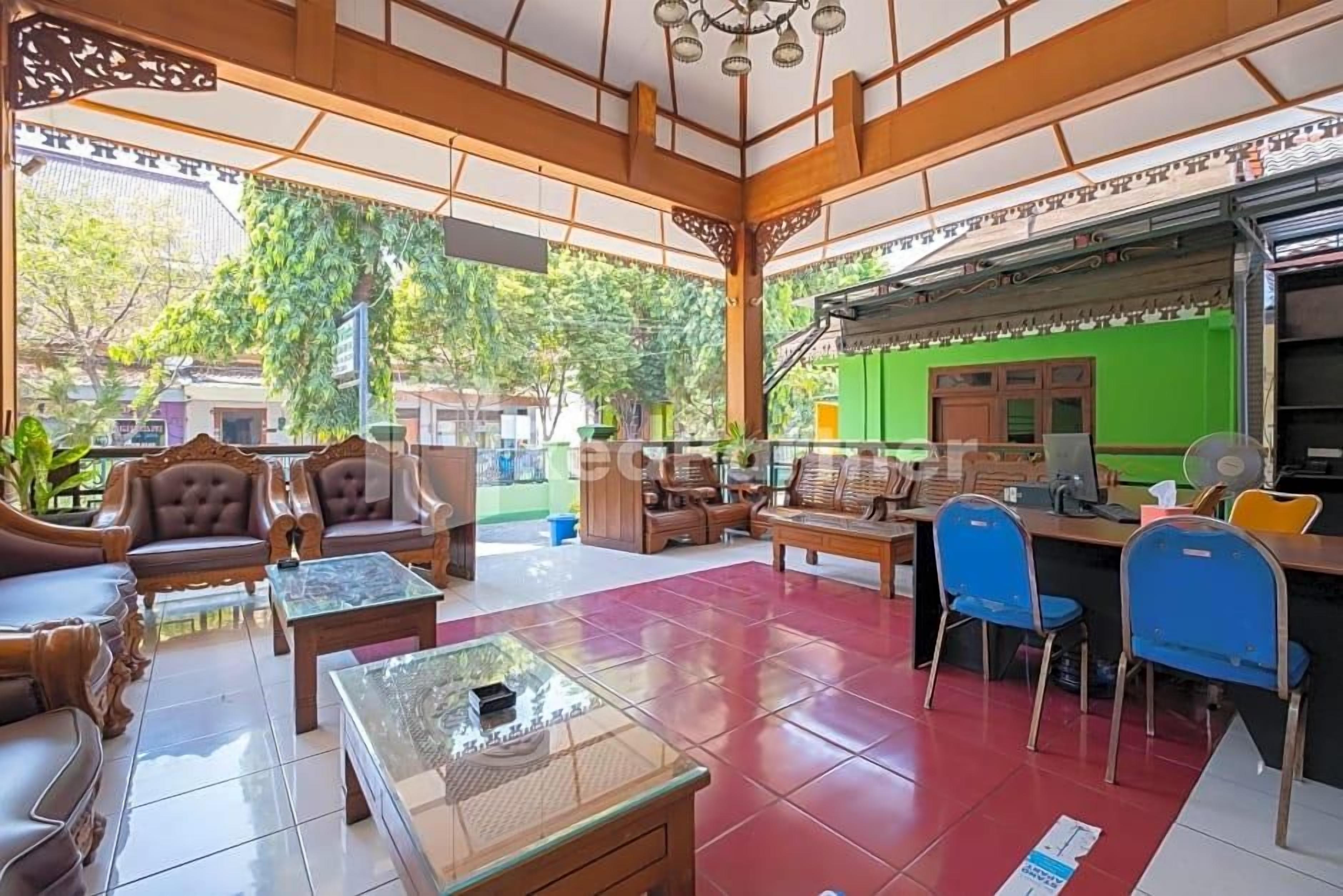 A spacious lobby with traditional wooden furniture, a green wall, and a view of the outdoors.