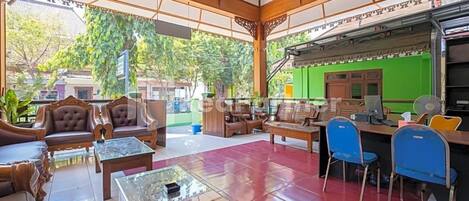 A spacious lobby with traditional wooden furniture, a green wall, and a view of the outdoors.