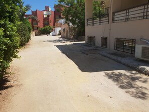 A narrow, unpaved alleyway with buildings on either side, some with barred windows and air conditioning units. - Lilly Rooms And Studios (Hurghada)