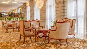 A grand lobby with ornate furniture, large windows, and a patterned carpet. - Suites At The Grand Palace Hotel (Addis Ababa)