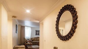 A hallway with a large ornate mirror, a sofa, and a chair. - Suites At The Grand Palace Hotel (Addis Ababa)