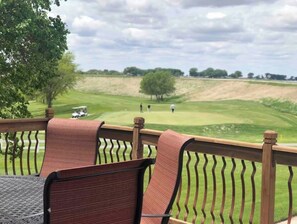 A deck with chairs overlooking a golf course.