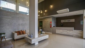 A hotel lobby with a reception desk, a sofa, a coffee table, and a plant.