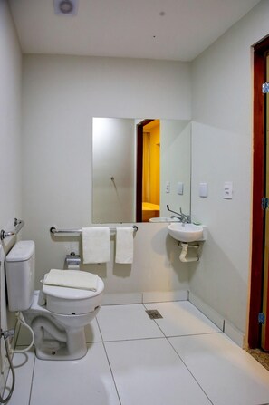 A modern bathroom with a toilet, bidet, sink, and mirror.