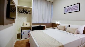 A hotel room with a bed, a desk, a wardrobe, and a mirror.
