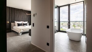 Ein modernes Schlafzimmer mit einem großen Bett und Blick auf die Stadt durch das Fenster.