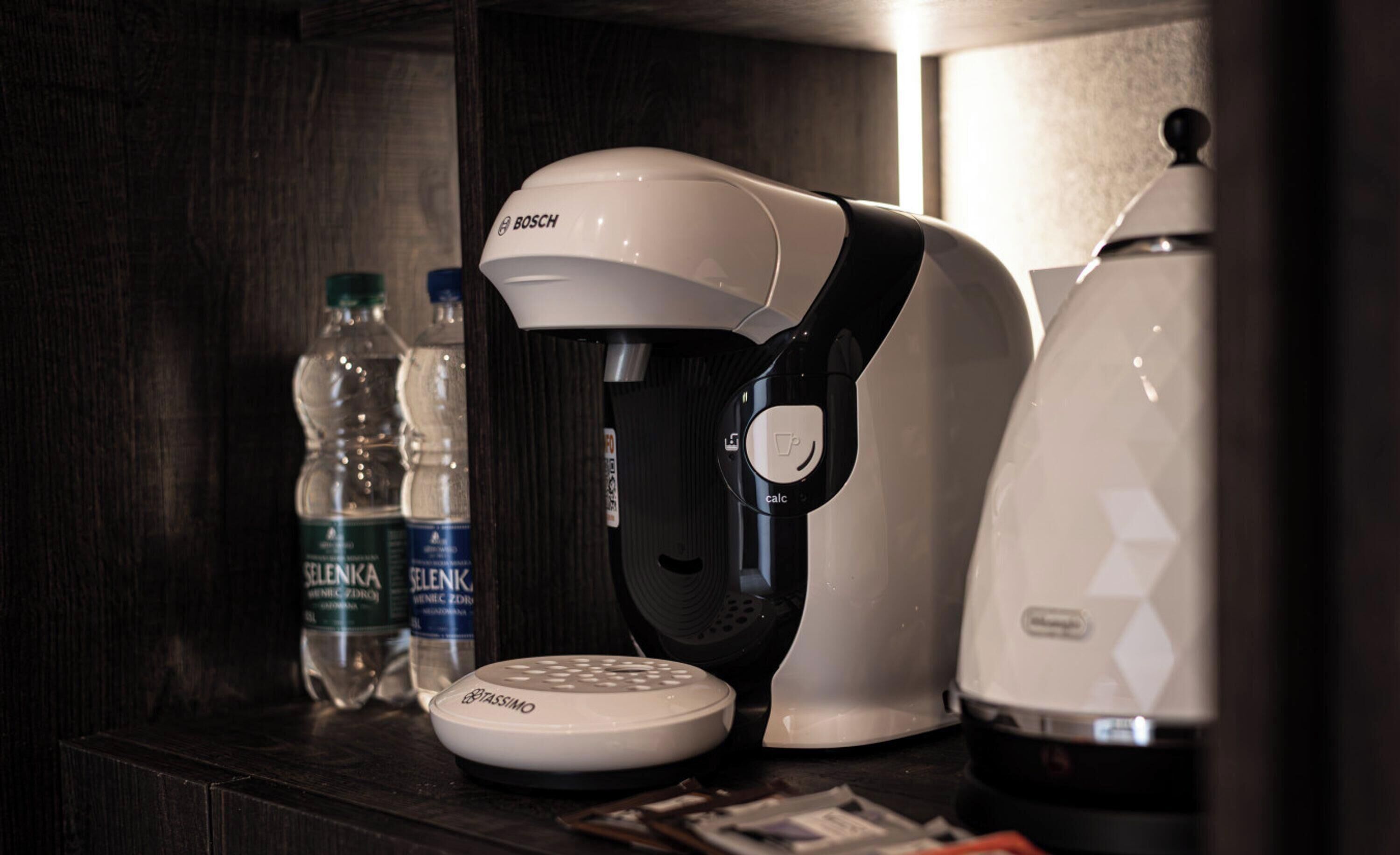 A coffee machine, a scale, and water bottles on a dark wooden surface.