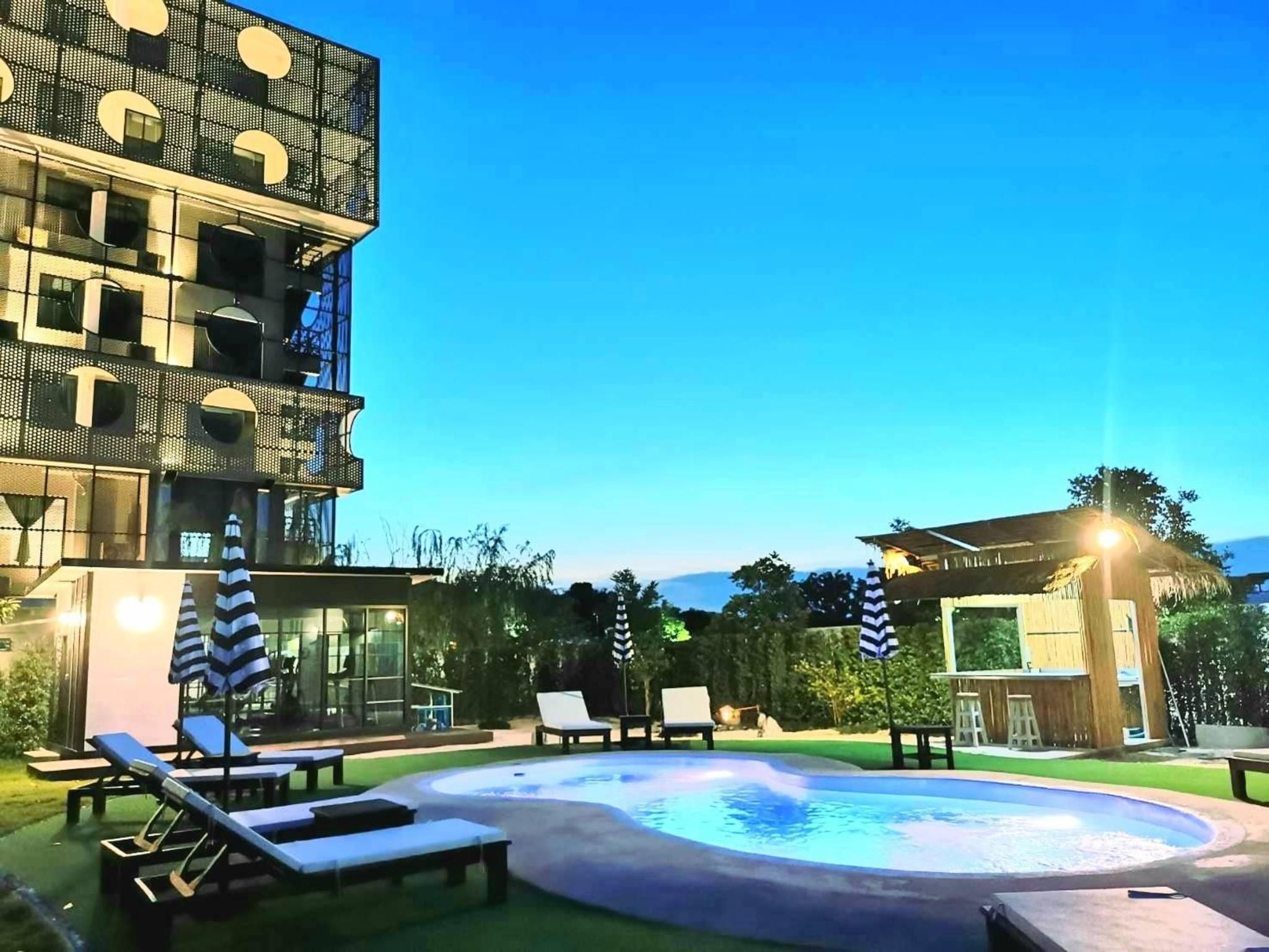 Un espace piscine doté de chaises longues, d’un jacuzzi et d’un bâtiment au design moderne.
