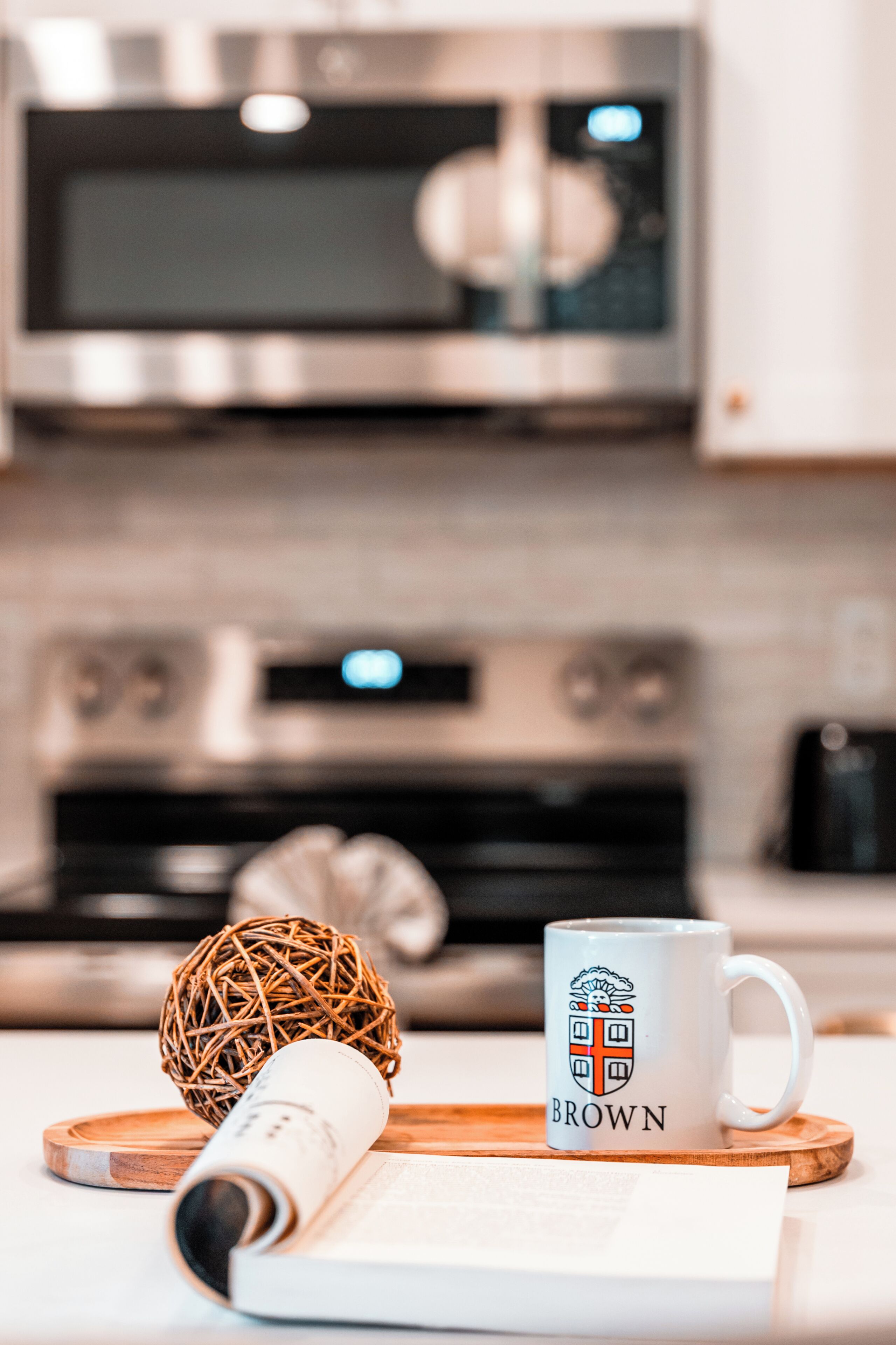 Una cocina con microondas, horno y una taza blanca con un logo de cresta.