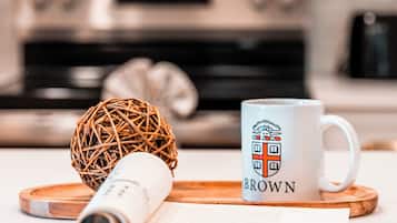 Una cocina con microondas, horno y una taza blanca con un logo de cresta.