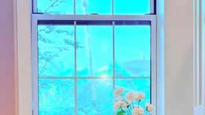 A bathroom with a window, a vase with flowers, a bowl, and towels on a table. - Fox Point Landing Residences (Providence)
