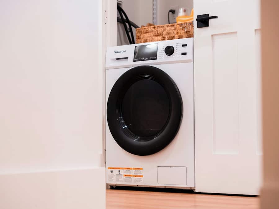 A front view of a white washing machine with a control panel and a black drum.