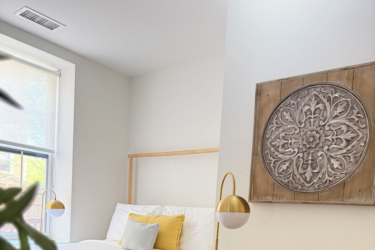 Une chambre à coucher comprenant un lit, une lampe de chevet, un élément décoratif mural et un fauteuil rond.