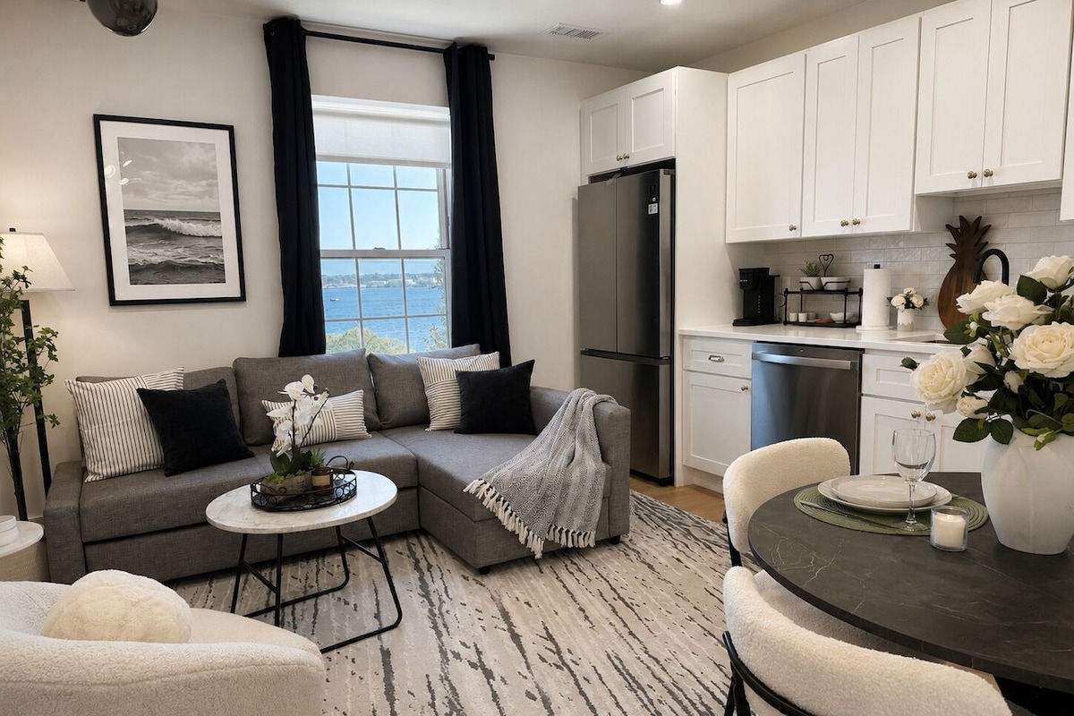 A modern kitchen with white cabinets, a refrigerator, and a dining area with a table and chairs.