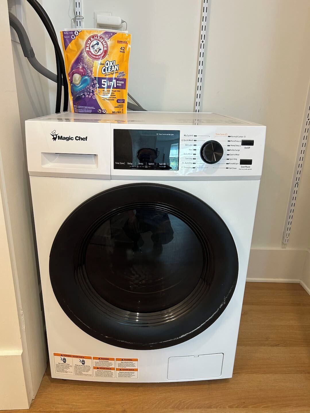 Eine Frontlader-Waschmaschine von Magic Chef mit Bedienfeld und Dosierbeutel obenauf.
