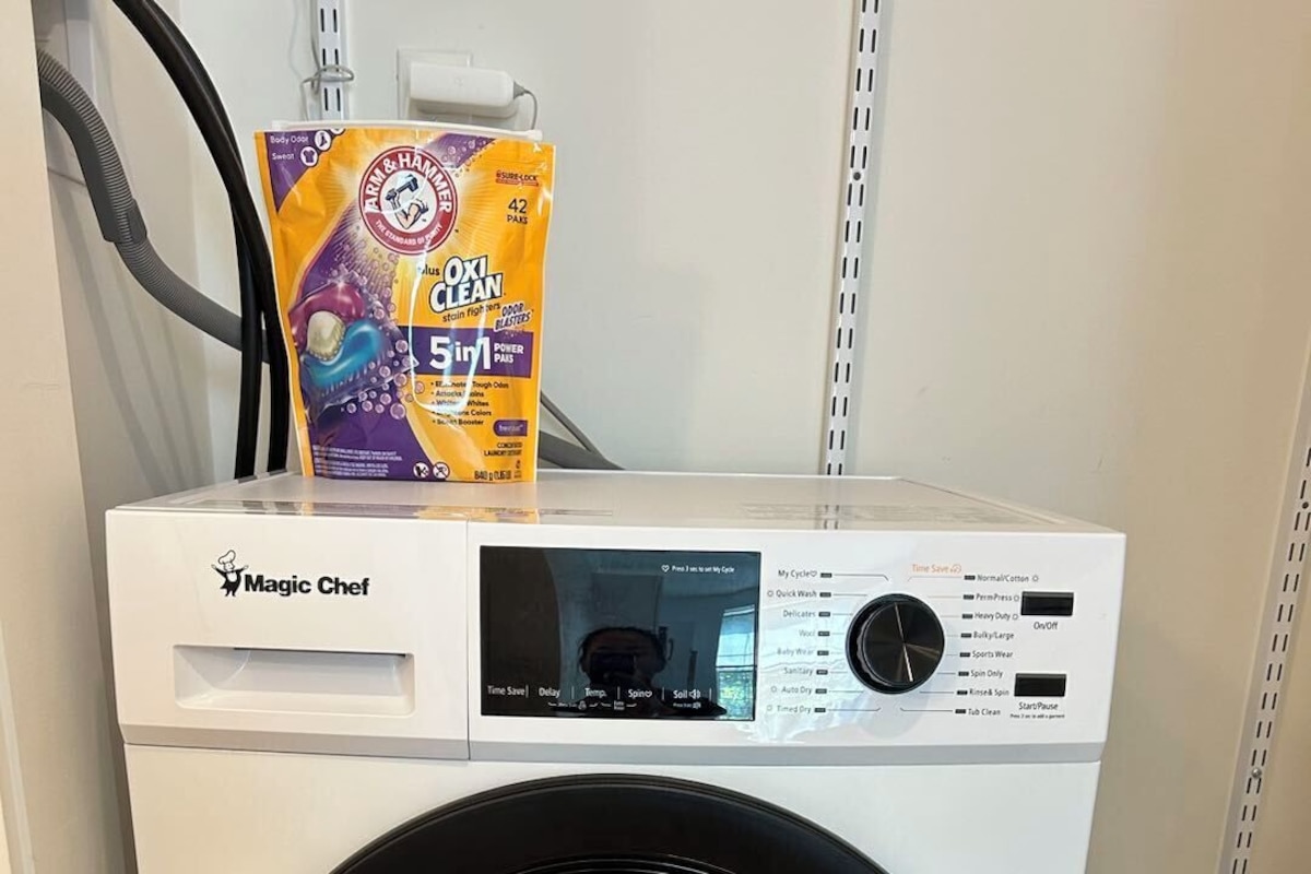 A front-loading Magic Chef washer with a control panel and a detergent bag on top.