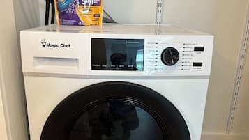 Eine Frontlader-Waschmaschine von Magic Chef mit Bedienfeld und Dosierbeutel obenauf.