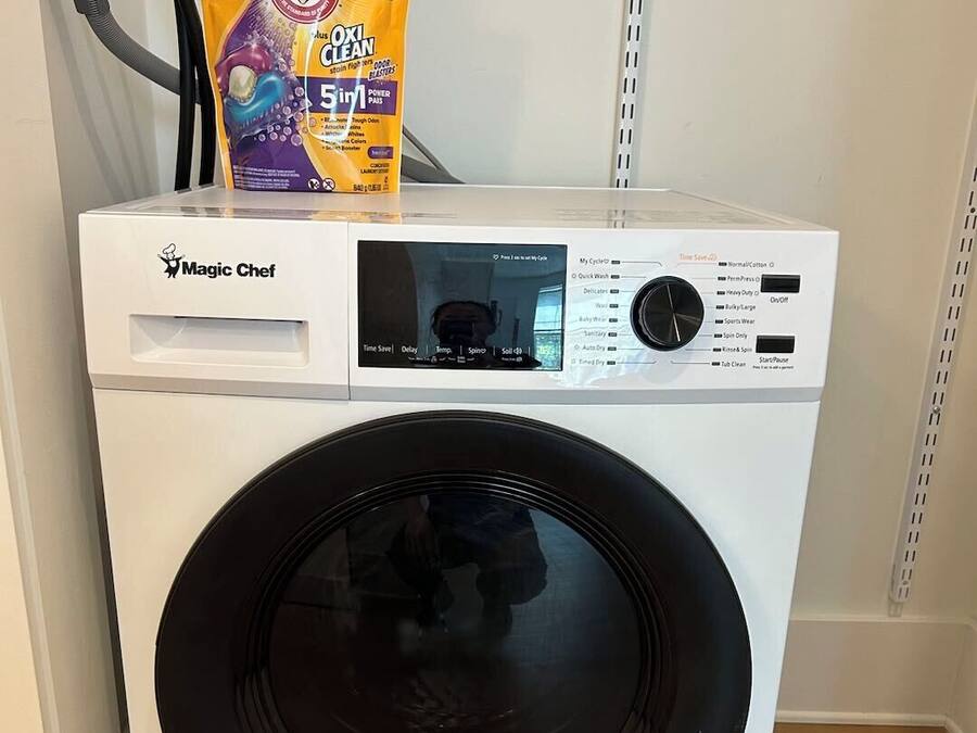 A front-loading Magic Chef washer with a control panel and a detergent bag on top.