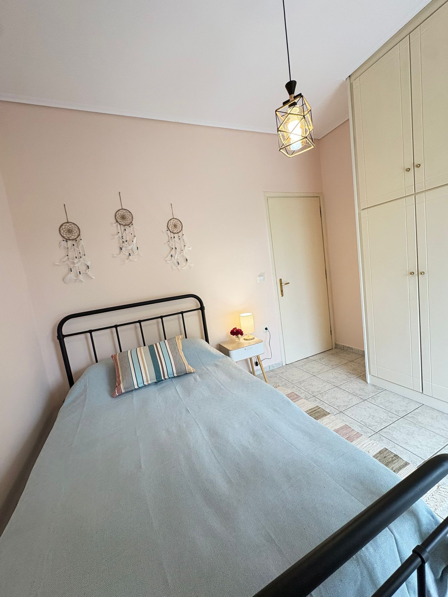 A bedroom with a bed, bedside table, lamp, wardrobe, and wall decorations.