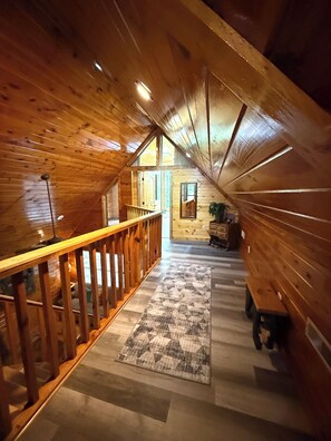 Ein Holzinnenraum mit schrägverdeckter Decke, einer Holzbalkonage und einem gemusterten Teppich.
