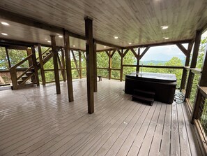 Eine überdachte Terrasse im Freien mit Holzboden, einem Whirlpool und einer Treppe.