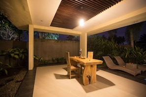 An outdoor patio with a wooden table, chairs, and lounge seating. - Asri Sari Resort Ubud (Ubud)
