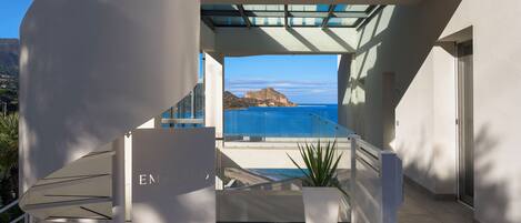 A modern building with a staircase leading to a balcony overlooking the sea.