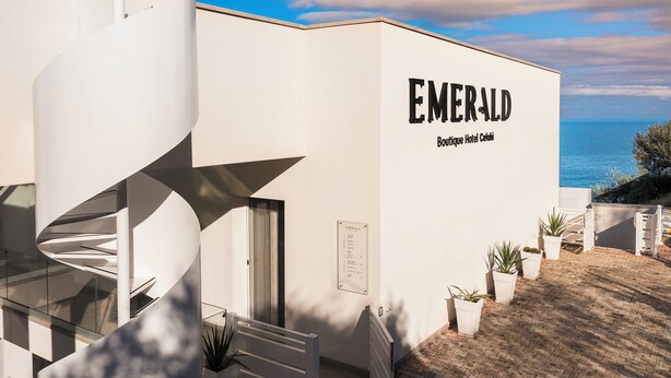 Moderni rakennus, jossa on kierreportaat, kyltti, jossa lukee ”EMERALD Boutique Hotel Cartagena”, ja näkymä merelle.