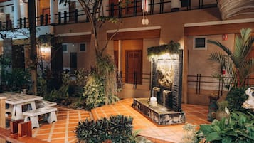 A courtyard with a fountain, potted plants, and outdoor seating.