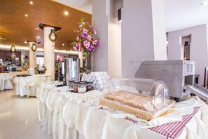 Montaje de bufé con una estación de café, una exhibición de frutas y una cesta de pan.