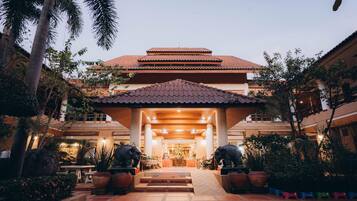 A hotel entrance with a tiled roof, a covered walkway, and a reception area with a statue.