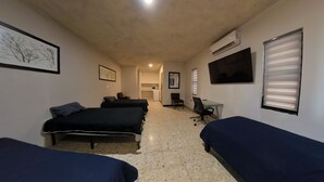 A room with two beds, a desk, a chair, a TV, and a microwave.